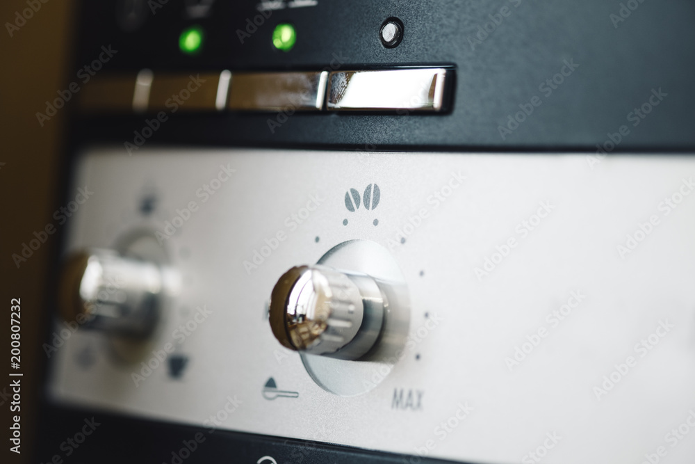 close up front view of modern automatic espresso coffee machine with silver buttons and signs close up front view of modern automatic espresso coffee machine with silver buttons and signs
