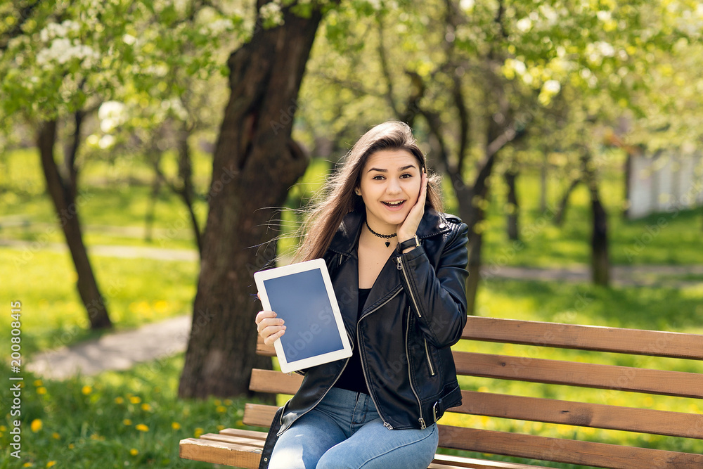 Young girl in the park with a tablet in hand. Young girl in the park with a tablet in hand.