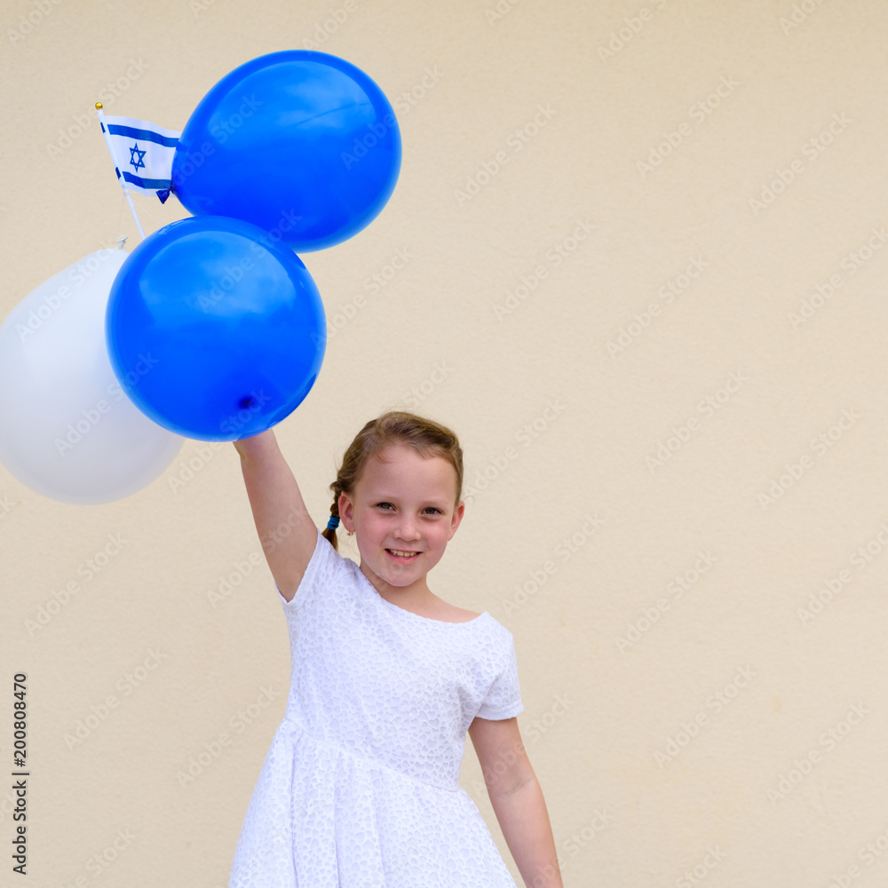 Portrait cute little girl standing, smiling and playing with blue and white balloons. Smiling child looking at camera and holding colorful air balloons and Israel national flag. Portrait cute little girl standing, smiling and playing with blue and white balloons. Smiling child looking at camera and holding colorful air balloons and Israel national flag.