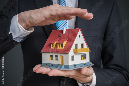 Home insurance concept. Man is holding model of house.
