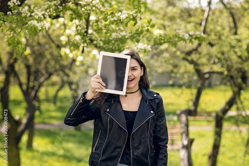 Portrait of young girl holding digital tablet in the park