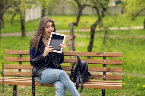 Portrait of young girl holding digital tablet in the park