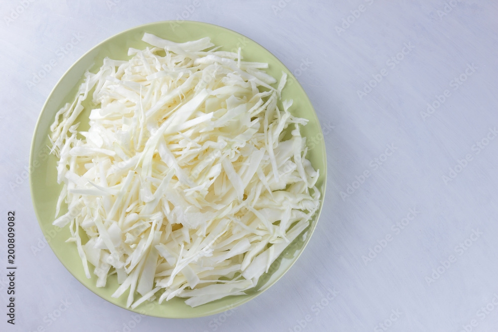 Chopped cabbage on white background, white cabbage on a green plate, copy space, top view, vegetarian food, fresh vegetables for salad, white background, minimalism, isolated Chopped cabbage on white background, white cabbage on a green plate, copy space, top view, vegetarian food, fresh vegetables for salad, white background, minimalism, isolated