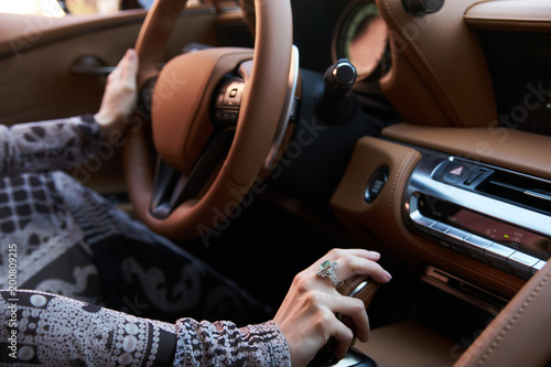 Obraz na plátně Blond young woman driving a sports car with luxury brown leather salon