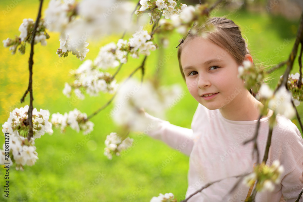 Adorable little girl in blooming cherry garden on beautiful spring day Adorable little girl in blooming cherry garden on beautiful spring day