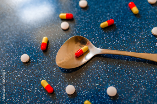 medicinal capsules in a spoon on a blue background photo
