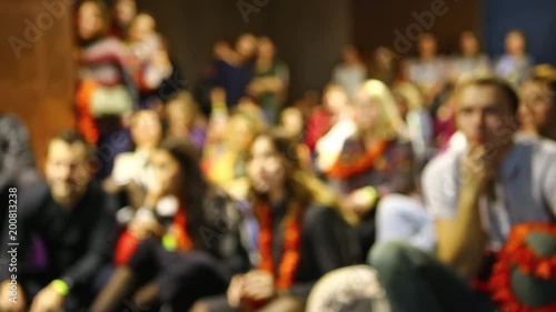 People listen and watch the presentation. Blurred background.