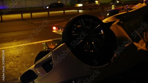 Night incident on the road. Car turned over on the road in the light of police flashers