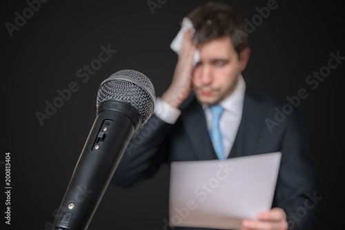 Fototapet Microphone in front of a nervous man who is afraid of public speech and sweating
