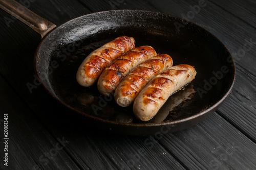 Black pan with delicious sausages on the grill on the kitchen table.