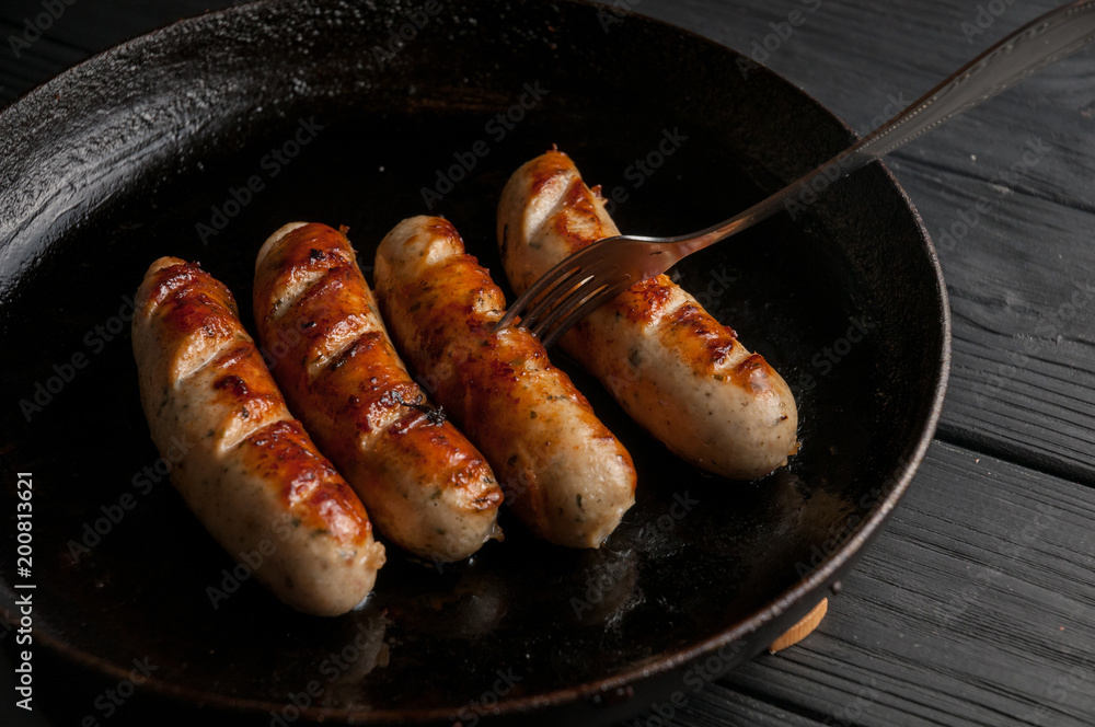 Black pan with delicious sausages on the grill on the kitchen table. Black pan with delicious sausages on the grill on the kitchen table.
