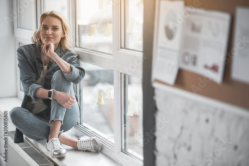 Fotografi Portrait of satisfied lady sitting by the window