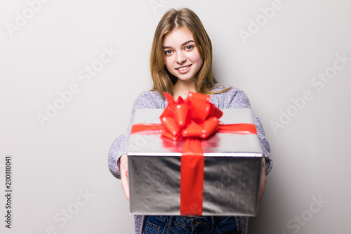 Portrait of a smiling cute teen girl opening gift box and looking at camera isolated on a white background