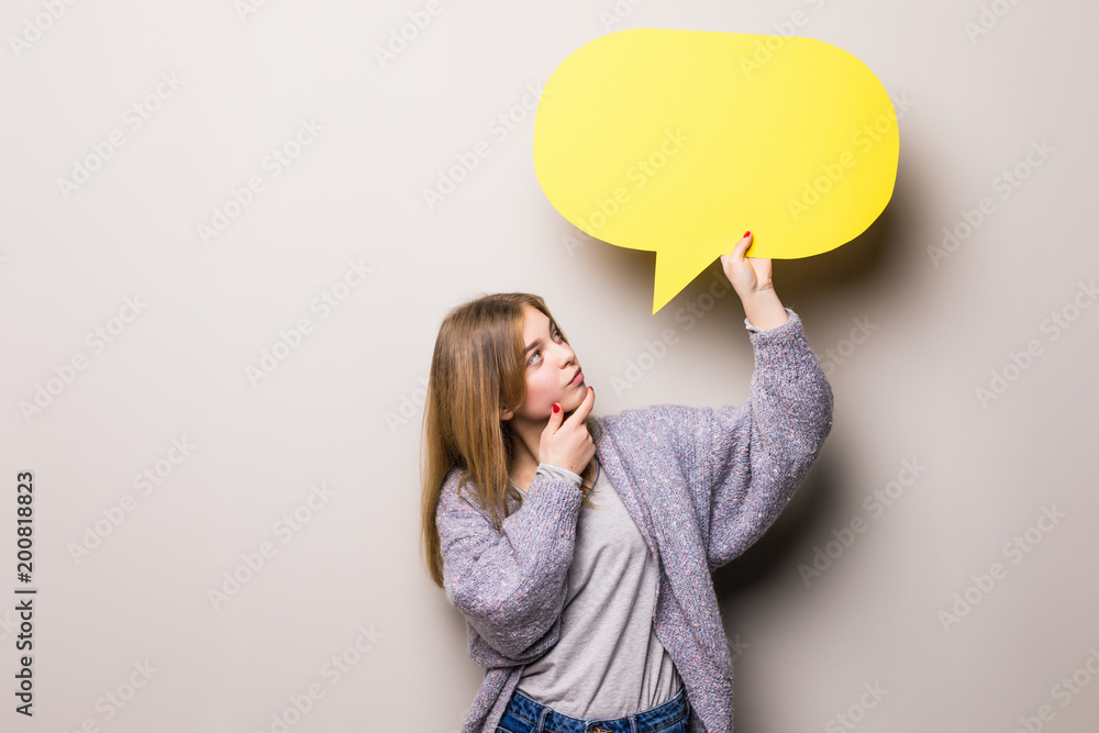 Fototapeta premium Young beautiful greaming girl holding a green bubble for text, isolated on a gray background