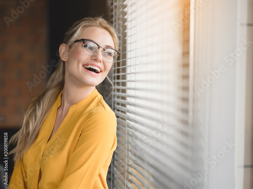 Portrait of excited young businesswoman is looking over the window jalousie with enjoyment