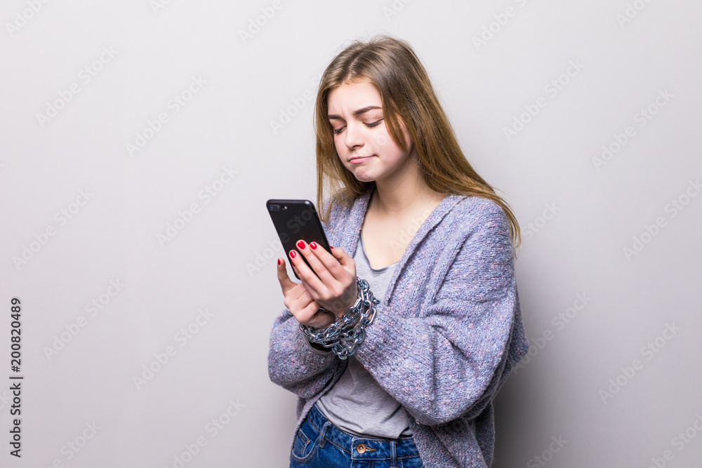 Naklejka premium Teen Girl with chain locked hands using a smartphone isolated on white background