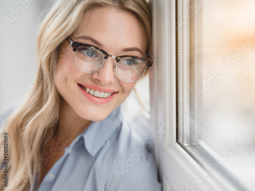 Portrait of happy blond businesswoman enjoying view from the window and smiling