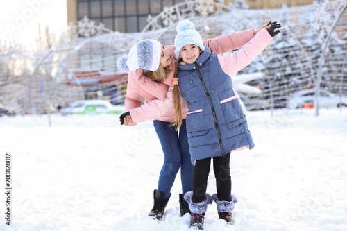 Portrait of cute little girl with mother outdoors on winter day