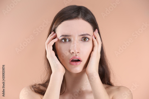 Teenage girl with acne problem against color background