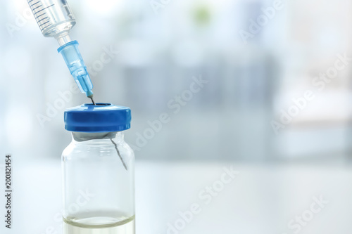Vial with vaccine and syringe on blurred background