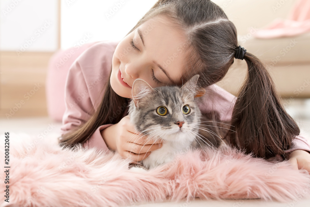 Cute little girl with cat lying on floor at home