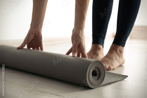Young woman with yoga mat indoors, closeup