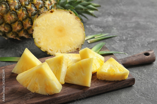 Wooden board with fresh sliced pineapple, closeup