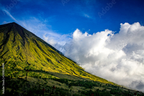 Green slopes of Gunung Inerie volcano with low clouds on the Indonesian island of Flores photo