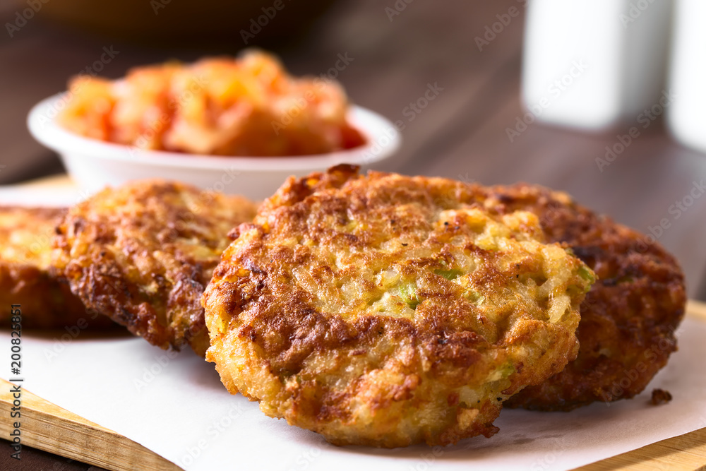 Rice patties or fritters made of cooked rice, carrot, onion, garlic and celery stalks, photographed with natural light (Selective Focus on the middle of the first patty)