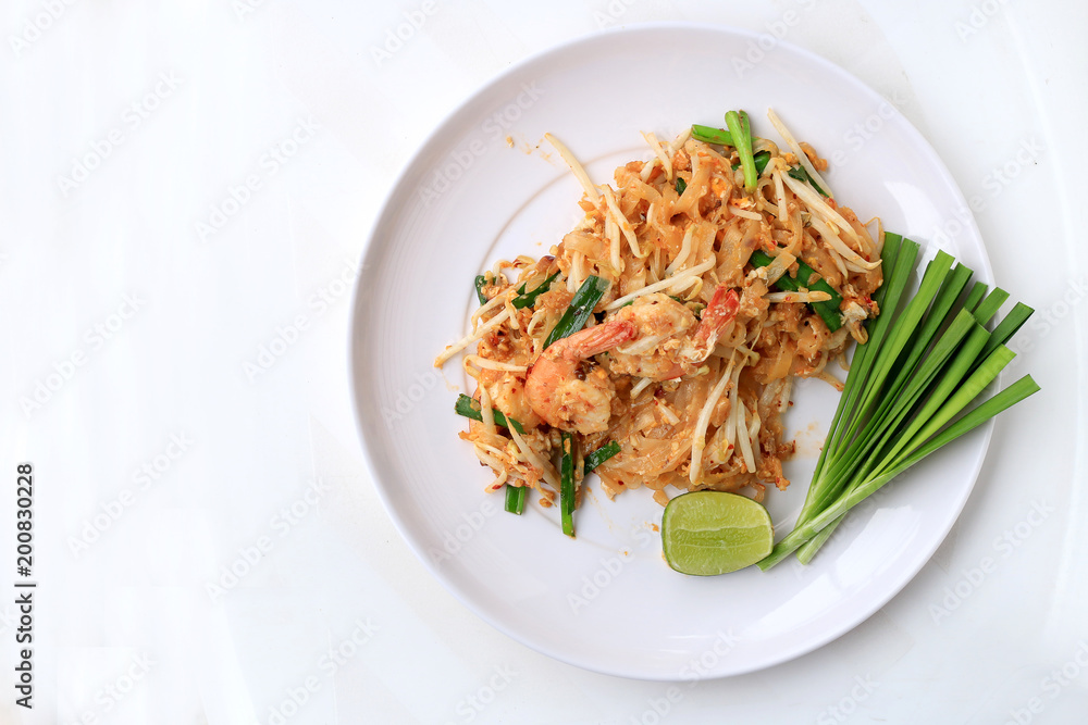 Pad Thai, stir-fried rice noodles with shrimp in white plate with slide lemon and green vegetable. The one of Thailand's national main dish. the popular food in Thailand. Thai Fried Noodles