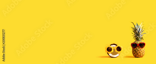 Pineapple and coconut wearing sunglasses on a yellow background