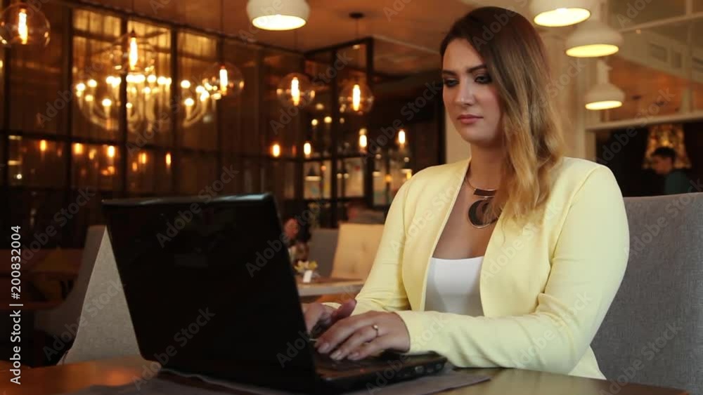 Business woman working using a mobile computer sitting at a table in a cafe. Business woman working using a mobile computer sitting at a table in a cafe.