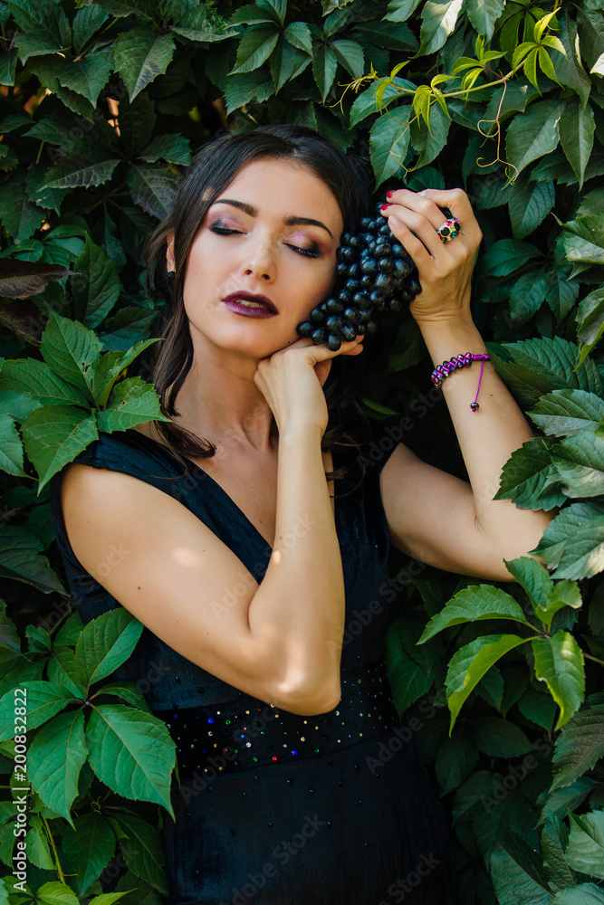 Portrait of young sexy brunette with black grapes. Portrait of young sexy brunette with black grapes.