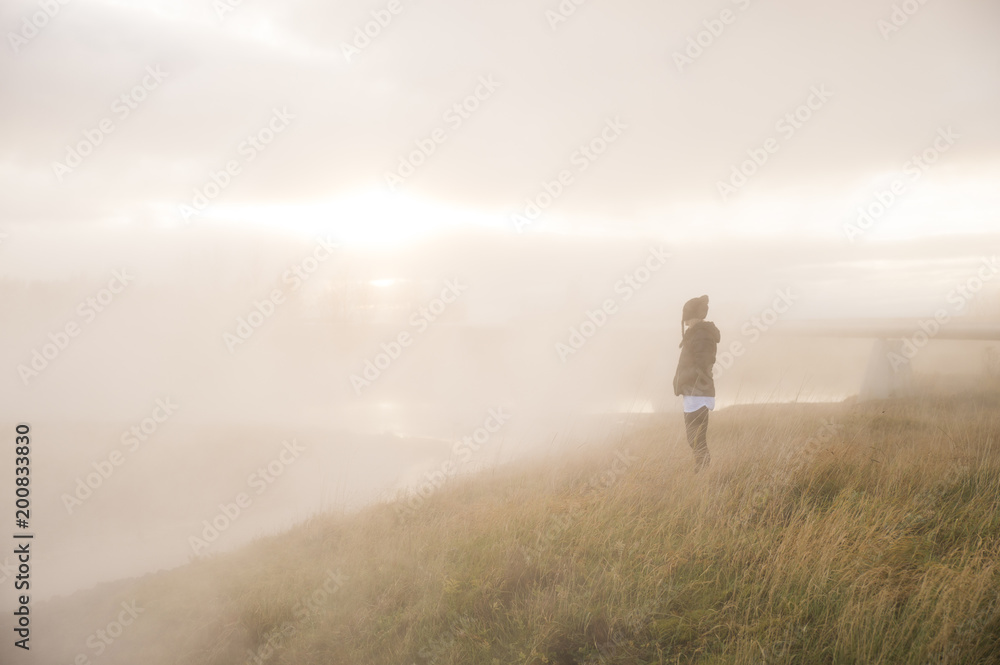 Woman standing in field with natural hot springs steam
