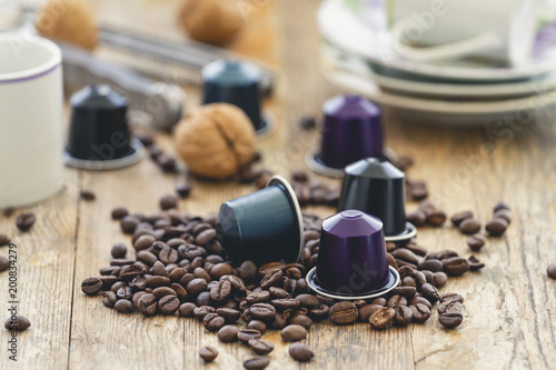Italian espresso coffee capsules or coffee pods with espresso cups and coffee beans on a rustic wood background. Coffee accessories composition photo