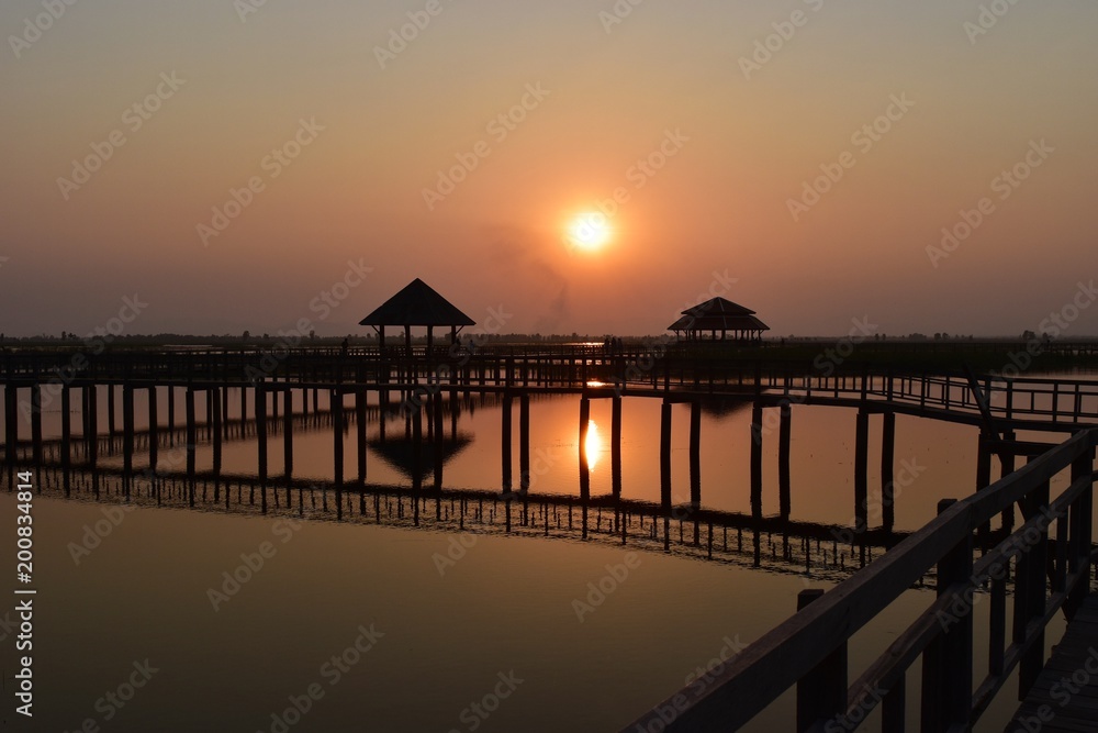 Fototapeta premium Khao Sam Roi Yot National Park ,Silhouette of Wooden bridge and pavilion, The path on the lagoon,Wetland,Sky turn orange at sunset ,Reflecting on water, Buang Bua, Thailand 