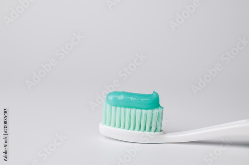Green toothpaste on a toothbrush on white background © ipuwadol