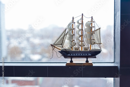 The model of a sailing ship stands on a misted window. The concept of travel. Dreams of a vacation. photo