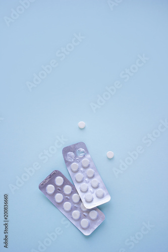 Two packing of white tablets with copy space on blue background. Medical concept treatment of diseases, sale of tablets, tablets in blister pack. Top view. Vertical