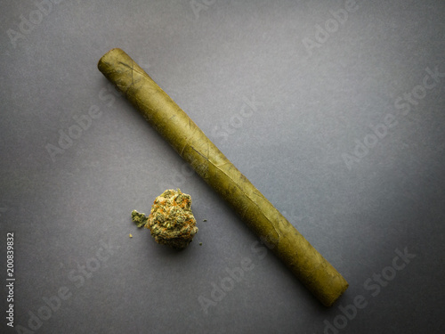 A marijuana bud and a cigarillo are isolated on a gray background. photo