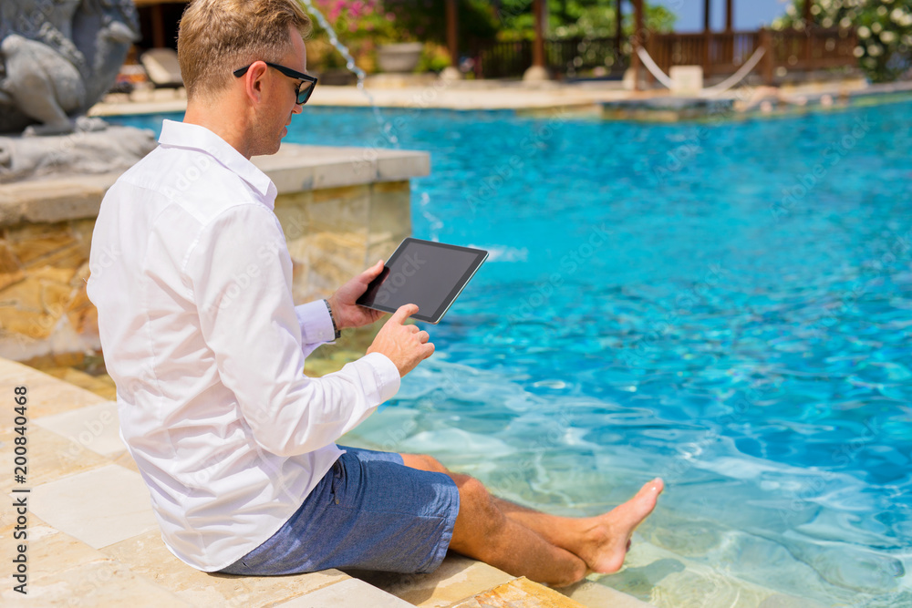 Man using tablet by the pool