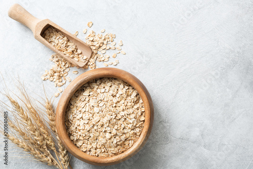 Organic rolled oats in wooden bowl on concrete background. Top view with copy space for text. Concept of healthy lifestyle, healthy eating, dieting, sport and fitness menu photo