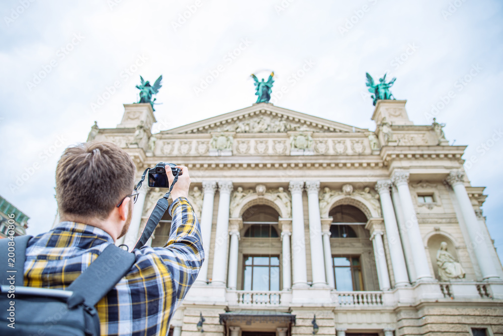 Obraz premium tourist man taking picture of old european architecture. copy space. travel concept