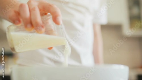 cook pours a Cup of kefir in a Cup photo