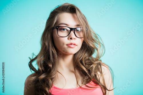 Close up portrait of serious, confident woman looking straight, isolated on blue background.