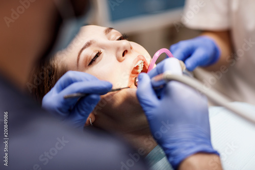Male dentist treating teeth to young woman patient in clinic. photo