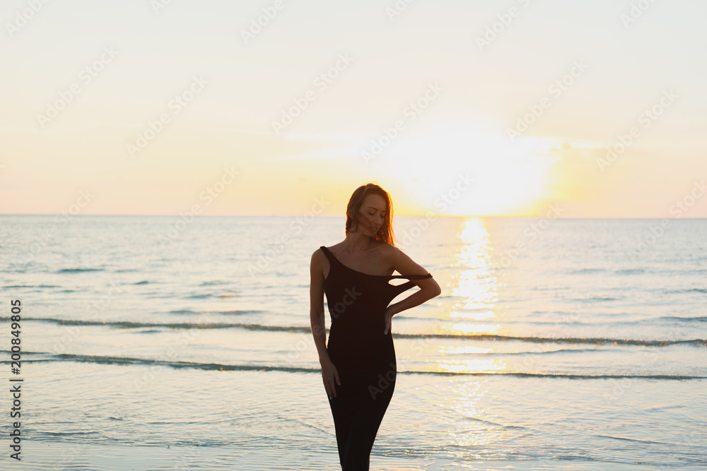 attractive woman posing in dress near ocean during sunset
