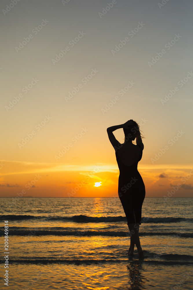 rear view of silhouette of woman posing in ocean during sunset