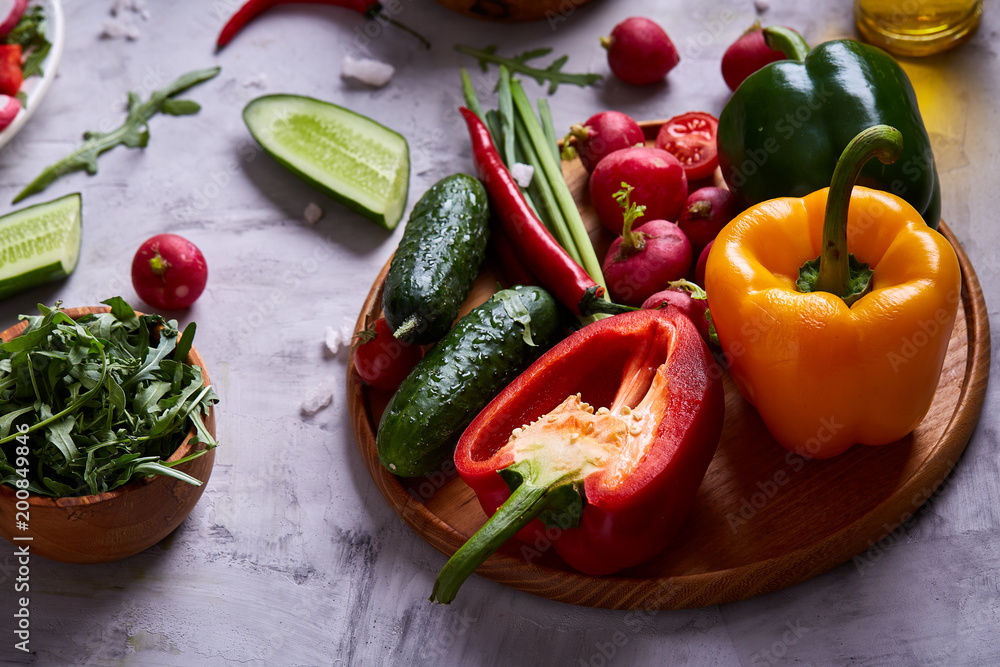 Still life of wooden plate with vegetables on white textured background, close-up, selective focus Still life of wooden plate with vegetables on white textured background, close-up, selective focus