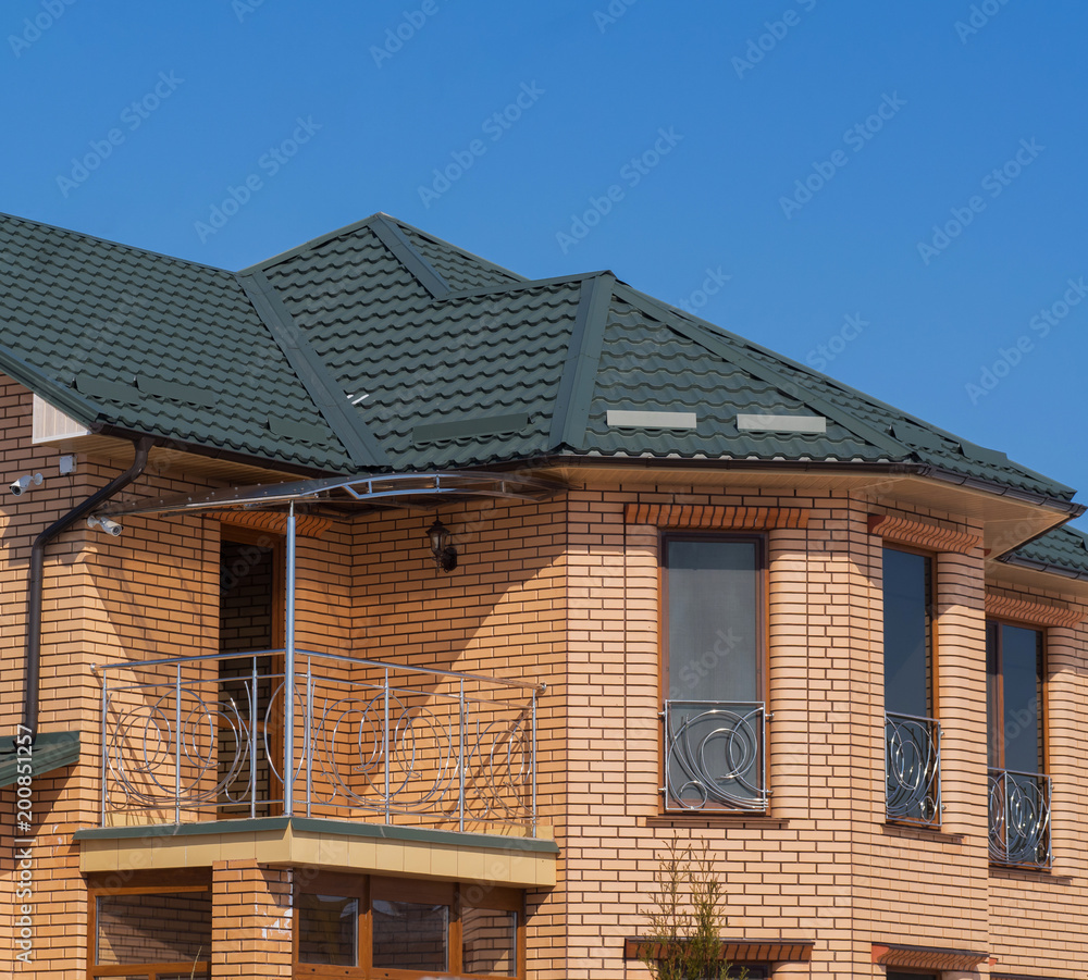 Modern cottage with balcony and brick facade. Blue sky background